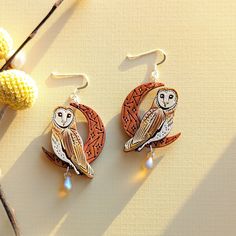 These celestial owl & moon earrings are incredibly detailed works of art that will add a whimsical touch to your fall and winter collection. These original beauties are inspired by barn owls ('Tyto alba') with their gorgeous big eyes, cream coloring, and unique spotted feathers. They are digitally illustrated and laser-etched on two layers of cherry wood featuring a dark-stained crescent moon etched with a constellation pattern and stars. The 'Night Owl' is meticulously hand-painted with shades Whimsical Moon-shaped Handmade Earrings, Handmade Whimsical Moon Earrings, Constellation Pattern, Owl Moon, Barn Owls, Polymer Crafts, Matte Metallic, Teardrop Beads, Barn Owl