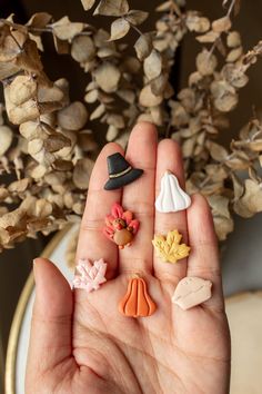 a person's hand holding five miniature fall decorations