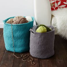 two crocheted baskets sitting on top of a wooden floor next to a white chair