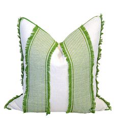 a green and white pillow with fringe trim