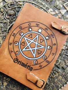 a brown leather journal with an inverted pentagramil on it