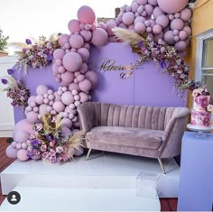 a couch sitting in front of a purple wall with balloons on it's side