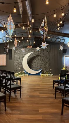 an empty room with chairs and lights hanging from it's ceiling in front of the moon