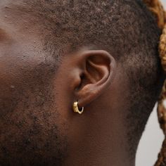 a man with dreadlocks wearing a pair of gold hoop earrings on his ear