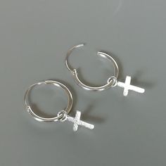 A PAIR of sterling silver hoops. Comes with a detachable dainty cross charm.The charm is multipurpose and can be used with a neck or bracelet chain too.Dimension: Hoop- 12 x 1 mm   Charm- 5 x 8 mm  Drop length- 20 mmPrice listed is for ONE PAIR These  are made of 925 hypoallergenic sterling silver. Most of my pieces come with a 925 stamp.Can be packaged in a gift box. I can include a personal message from you if needed_______________________________________You are welcome to contact me at...   b Dainty Handmade Silver Huggie Earrings, Silver Minimalist Huggie Earrings With Charms, Silver Dangle Hoop Earrings With Charms, Sterling Silver Hoop Earrings With Charms, Minimalist Silver Cross Earrings, Silver Sterling Silver Cross Earrings, Silver Sterling Silver Charm Hoop Earrings, Pierced Cross Sterling Silver Earrings, Nickel-free Cross Hoop Earrings As Gift