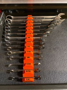 several wrenches are lined up in a row on top of a metal tray with measuring tape