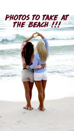 two women standing on the beach with their arms around each other making a heart shape