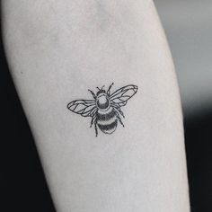 a black and white photo of a bee tattoo on the left inner arm or leg