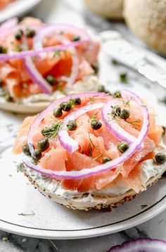 an open face sandwich with salmon, capers and onions on it sitting on a plate