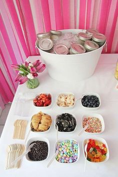 an assortment of desserts are displayed in bowls on a table with pink and white stripes