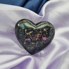 a heart shaped glass object sitting on top of a white cloth