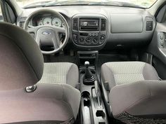 the interior of a small car with grey seats and dashboard controls, including steering wheel