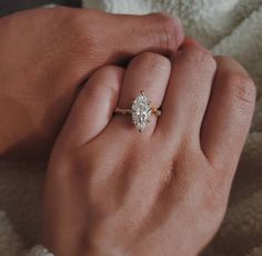 a woman's hand holding an engagement ring with a pear shaped diamond on it