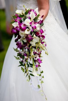 a bride holding a bouquet of purple and white flowers