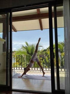 a person doing a handstand in front of a sliding glass door on a patio