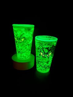 two green cups with yellow eyes glow in the dark, while one is lit up