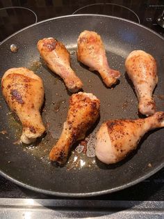 chicken legs are cooking in a pan on the stove