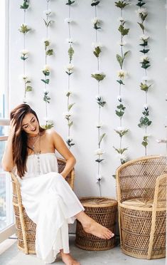 a woman sitting in a chair next to two baskets with flowers on the wall behind her