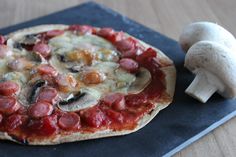 a pizza sitting on top of a wooden table next to a mushroom