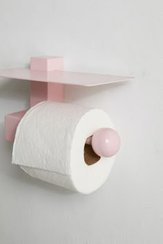 a pink toilet paper holder on the wall