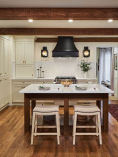 a kitchen with an island, stove and two stools in front of the counter