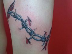 a close up of a person's leg with a tattoo on it that has barbed wire