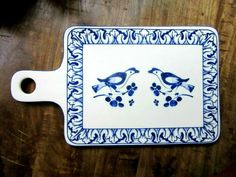 a blue and white tray with two birds sitting on it's side, next to a bottle opener