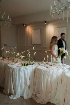 a bride and groom standing in front of a table with flowers