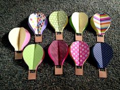 six hot air balloons are lined up on the floor, each with different patterns and colors