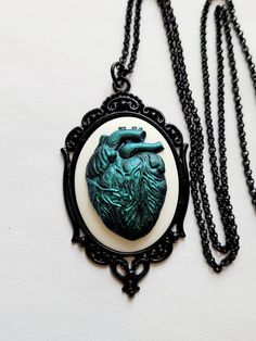 JUST LISTED Green Iridescent Heart Anatomy Gothic Rockabilly Cameo black Necklace Pendant Victorian Jewelry Hand painted cameo If you are wanting a specific color please feel free to contact me and I will do my best to create what you are searching for. Victorian Jewelry substantial in size at just a little over 2 INCHES Long Center is 40mmx30mm **MATCHING ITEMS IN OUR STORE BADGE HOLDER BROOCH HAIR PINS - CLIPS** **thank you for taking the time to look at our items. Each item is handcrafted and Heart Anatomy, Halloween Necklace, Jewelry Hand, Cow Skull, Faux Pearl Necklace, Black Necklace, Halloween Jewelry, Victorian Jewelry, Gemstone Necklace Pendant