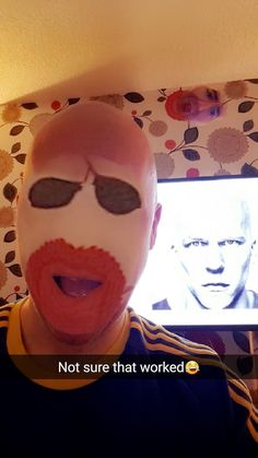 a man with his face painted red and white, has an odd look on his face as he stands in front of a television