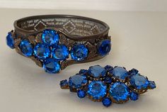 "Art Deco blue rhinestone Czech bracelet and brooch. Unmarked.  1920-s  brooch -  2 1/8\" x 1 1/8\" , simple \" C \" clasp  bracelet - approximately 6 7/8\" x  1 1/4\" w. ( Photo: my wrist - 6.75\" )  Very good condition  00954 11/09/22" Antique Blue Jewelry With Brooch, Blue Art Deco Formal Brooch, Vintage Sapphire Brooch Jewelry, Antique Blue Bracelet Jewelry, Vintage Blue Jewelry Brooch, Blue Brooch For Wedding Jewelry, Blue Wedding Brooch Jewelry, Vintage Blue Brooch, Formal Blue Costume Jewelry Bracelets