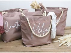 three brown bags with white writing on them sitting on top of a wooden table next to some dry grass