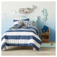 a child's bedroom with blue and white striped bedding, seahorse wall decals and wooden toy chest