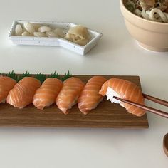 sushi and chopsticks sit on a wooden board