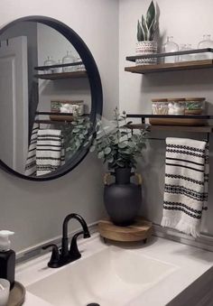 a bathroom sink sitting under a mirror next to a black and white potted plant