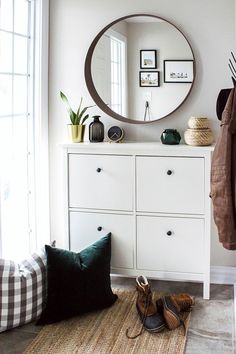 a white dresser sitting next to a mirror on top of a wall