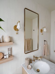 a bathroom with a sink, mirror and shelves on the wall next to each other