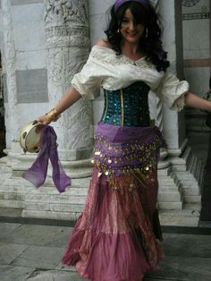 a woman wearing a purple and gold belly dance skirt with her hands in her pockets