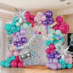 an arch made out of balloons and snowflakes is displayed in the center of a room