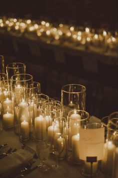 many candles are lit on a table with silverware