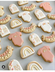 baby shower cookies are arranged in rows on a table with white and pink icing