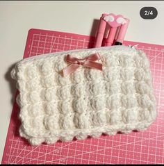 a crocheted pencil case sitting on top of a cutting board