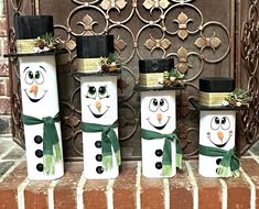 three snowmen with hats and green scarfs on their heads are sitting in front of a fireplace