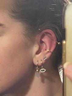 a close up of a person holding a cell phone with ear piercings on it