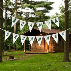 there is a sign that says camp saunawah hanging from the trees in front of a log cabin