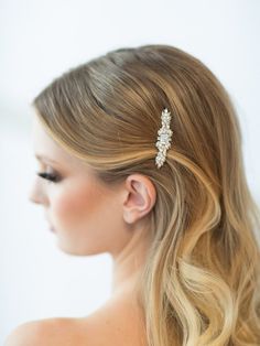 a woman with long blonde hair wearing a bridal hairstyle and a crystal brooch