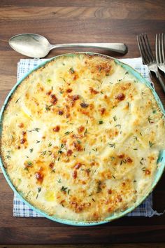 a blue plate topped with cheese covered casserole next to silverware