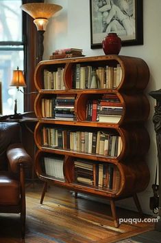 a book shelf with many books on it in a living room next to a chair