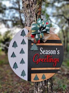 a sign that says season's greetings hanging on a tree